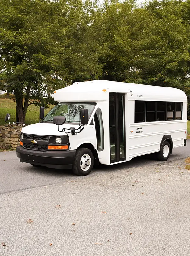 White activity bus in front of a row of trees