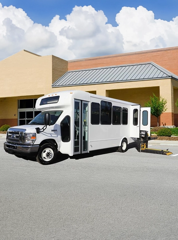 white wheelchair fitted bus parked in front of a building